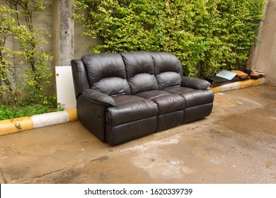 Discarded Worn Out Artificial Leather Sofa Thrown Away At Roadside In Front Of Garbage Room, Waiting For Recycle Process, Climate Change Concept