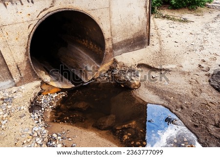 Discharge of sewage from an industrial enterprise. Large pipe and stream of chemical waste. Close-up. Selective focus
