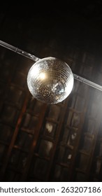disco ball hanging from ceiling with dramatic spotlight in dark room