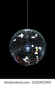 A disco ball is hanging from a string. The ball is black and white with a shiny surface