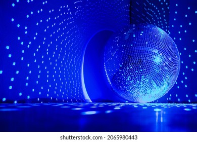 Disco ball reflecting blue light in a dark hall for discos. Disco on the floor. Copy space.
