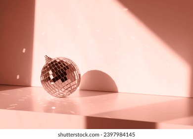 Disco ball in sunlight with reflections on white background. Geometric shadows peach color of the year 2024 - Powered by Shutterstock