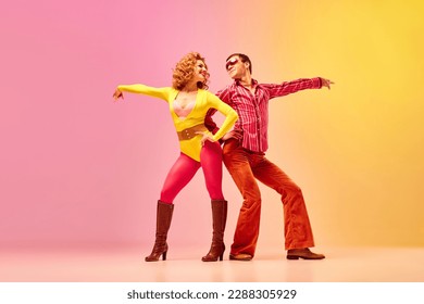 Disco dance. Stylish expressive excited couple of professional dancers in retro style clothes dancing over pink-yellow background. Concept of 70s, 80s fashion style, music and emotions