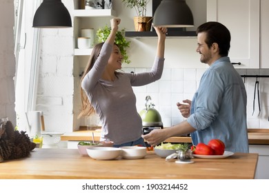 Disco On Kitchen. Happy Millennial Couple Engaged In Cooking Meal At Home Rest Relax Relieve Stress. Laughing Husband And Wife Dance Modern Dances Listen To Music Enjoy Improvised Party At Kitchen