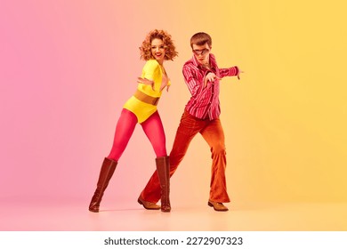 Disco style. Young emotional man and woman, professional dancers in retro clothes dancing dance over pink-yellow background. American culture, 1970s, 1980s fashion, music concept - Shutterstock ID 2272907323