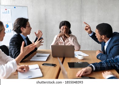 Discontented Coworkers Shouting At Unhappy Victimized Businesswoman Sitting At Table In Modern Office. Adult Bullying At Work, Conflicts And Disagreement, Business Communication Problems Concept