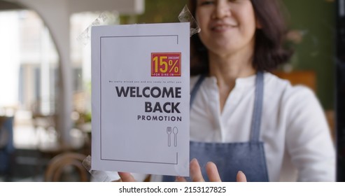 Discount campaign banner in asia bakery cafe coffee shop after post covid-19 coronavirus pandemic. Happy woman work smile stick label text placard logo on door glass. SME buying coupon offer.