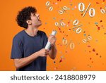 Discount offer. Happy young man blowing up party popper on orange background. Confetti and percent signs in air