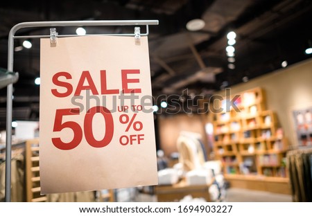 Discount percentage sign display in  fashion department store during sale season period. Sale tag of offering special promotion hanging in shopping mall, Blurred department store background.