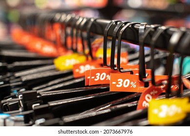 Discount sale tags 30% off, on hangers with clothes in casual, home or sport clothing store. Fashion concept, discount season, black friday, offline shopping, gimmicks, holiday sales. Side view.
