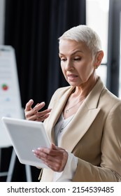 discouraged businesswoman gesturing near digital tablet in office