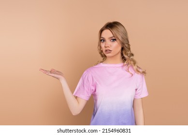 discouraged woman with wavy hair pointing with hand isolated on beige