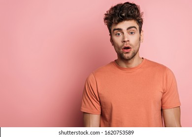 discouraged young man looking at camera on pink background