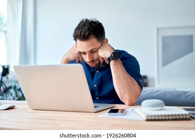 discouraged young man looking with disappointment on laptop while working at home