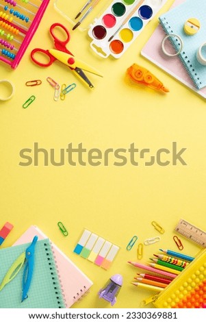 Discover the joy of education for small kids through this top view vertical image: a captivating arrangement of vibrant school supplies on a sunny yellow surface, with space for text or promotions