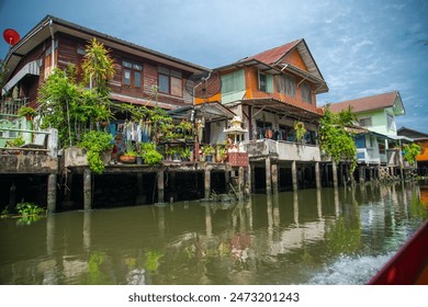 Discover the unique and resilient lifestyle of Bangkok's water slums with this captivating image. The photo captures a dense cluster of makeshift houses built on stilts over the water, showcasing the - Powered by Shutterstock