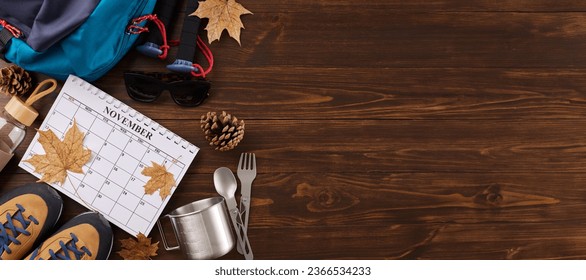 Discovering the splendor of autumn on a hike. Top view photo of calendar, metal utensils, trekking boots, backpack, bottle, trekking sticks, cones, fallen leaves on wooden background with promo area - Shutterstock ID 2366534233