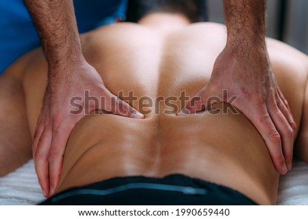 Discus Hernia manual massage treatment. Physical therapist massaging lower back.