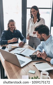 Discussing Business Details. Young Modern Colleagues In Smart Casual Wear Working Together While Spending Time In The Creative Office