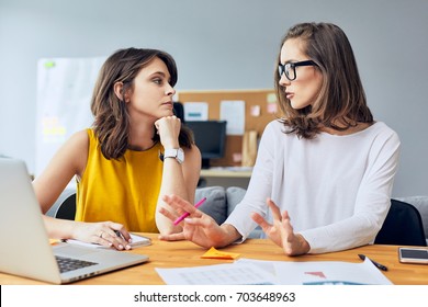 Discussing Business Matters. Two Attractive Young Coworkers Talking About Their Startup Business In Office