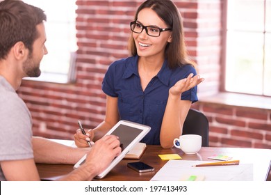 Discussing Business. Two Cheerful Business People In Casual Wear Talking And Gesturing While Sitting At The Table 