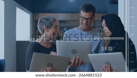 Discussing data three professionals collaborating in office lounge, with three silver laptops. Collaboration, teamwork, modern, casual, startup, communication, workspace