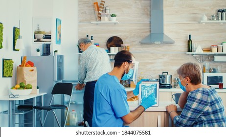 Discussing diagnosis with senior patient during home visit looking at x-ray. Elderly person medical radiography by male nurse for disease prevention, examining retired senior woman. - Powered by Shutterstock