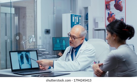 Discussing Lungs X Ray Result With Young Female Patient. Elderly Senior Experienced Doctor Talking With Patient About Lungs, X Ray Pneumonia, Cancer, Examination Specialist Consulting Diagnosis In