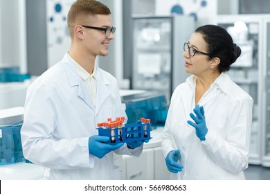 Discussing Results. Senior Female Scientist Talking To Her Handsome Young Male Colleague While Working With Blood Test Smaples Teamwork Professionalism Internship Medicine People Healthcare Concept