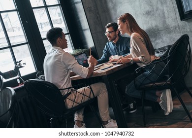Discussing risky ideas. Group of young confident business people discussing something while spending time in the office - Shutterstock ID 1047940732