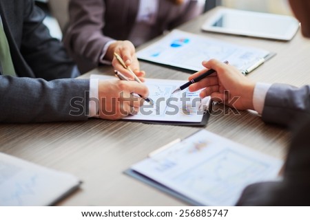 Discussing the scheme. Side view of business people, pointing handles on the chart together, sitting at the table