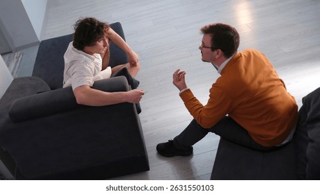 A discussion between a psychologist and a client. View from above. The student turned to his therapist with a request to work out his childhood traumas. Specialist consultation. The men's dispute