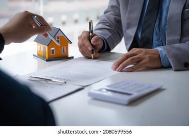 Discussion with a real estate agent, House model with agent and customer discussing for the contract to buy, get insurance or loan real estate or property. - Shutterstock ID 2080599556
