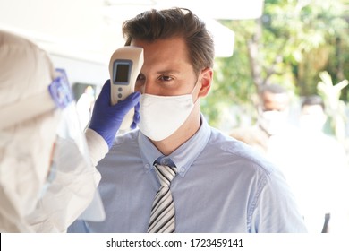 Disease control experts  use an Infrared thermometer equipment to check the temperature on the forehead and use alcohol gel to screen the patients addicted to Covid before entering the building. - Powered by Shutterstock