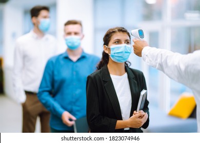 Disease control experts use an Infrared thermometer equipment to check the temperature on the forehead before entering at office. Сhecking the temperature of office workers. Covid-19. - Powered by Shutterstock