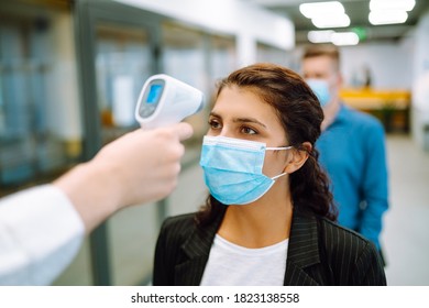 Disease control experts use an Infrared thermometer equipment to check the temperature on the forehead before entering at office. Сhecking the temperature of office workers. Covid-19. - Shutterstock ID 1823138558