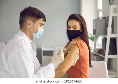 Disease Prevention, Immunization And Vaccination Campaign Concept. Doctor Giving A Flu Injection To Patient. Young Woman In Medical Face Mask Getting Covid-19 Vaccine Shot At The Clinic Or Hospital