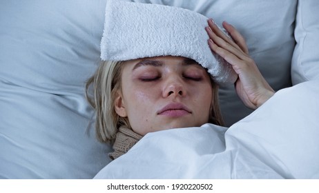 Diseased Woman Lying With Closed Eyes And Touching Compress On Forehead