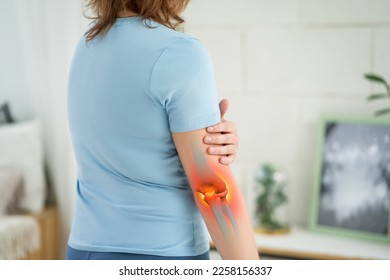 Diseases of the elbow joint, bone fracture and inflammation, woman suffering from pain in cubit, painful area highlighted in red, BeH3althy concept photo - Shutterstock ID 2258156337