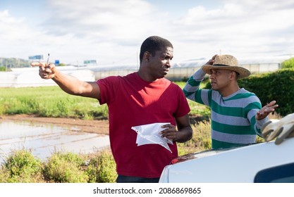 Disgruntled African American Farmer Holding Papers, Reprimanding Hispanic Contractor For Poor Job Outdoors