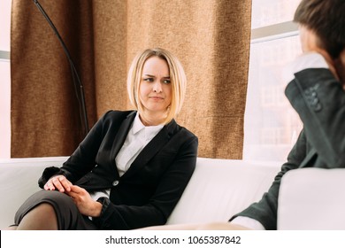 Disgruntled Girl Sitting In The Office On The Couch Opposite The Man