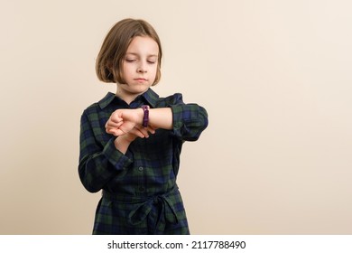 Disgruntled Kid Little Girl 9s Wearing Plaid Shirt Dress Looks At A Smart Watch Fitness Band. Children Time Management Concept