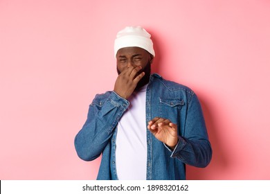 Disgusted Black Man Shut Nose And Cringe From Awful Smell, Showing Refusal Gesture, Standing Over Pink Background