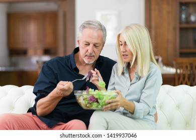 Disgusted Couple Eating Salad On A Couch