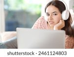 Disgusted woman with headphone and laptop looks at you sitting at home