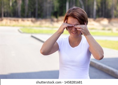 Disgusted Young Woman Is Rubbing Her Eyes Standing Outdoors, In A Park