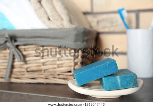 Dish with blue handmade soap bars on table in\
bathroom. Space for text