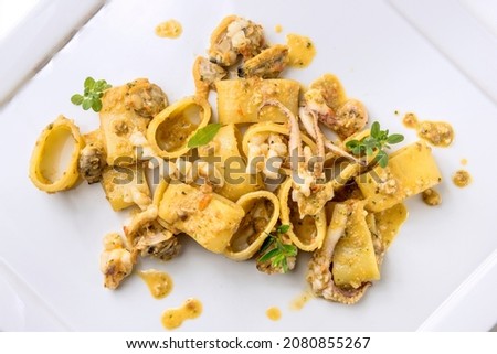 Dish of calamarata pasta with squid and clams isoated on white background