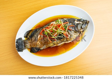 A dish of Cantonese steamed grouper on wooden table	