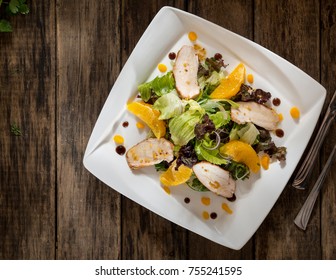 Dish Of Chicken And Salad In A White Square Plate On Wooden Boards, Top View